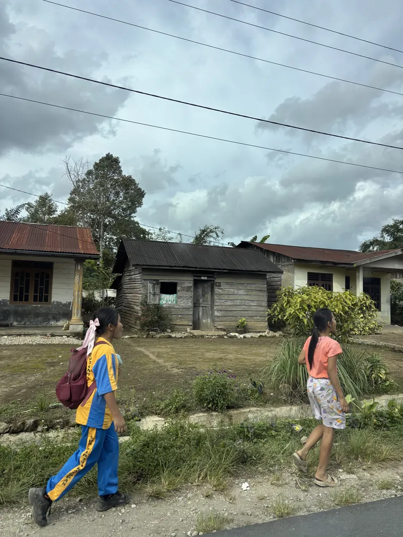 Two girls walking along a path through a mountain village in Indonesia