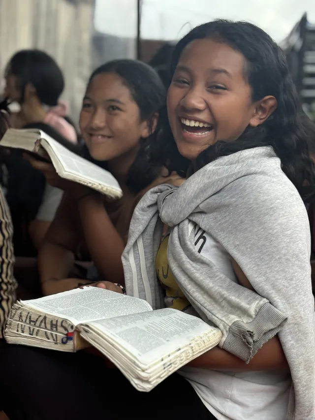 Teenage girls laughing together with open Bibles