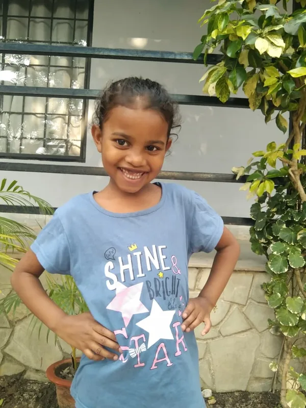 A smiling girl in a blue T-shirt with her hands on her hips