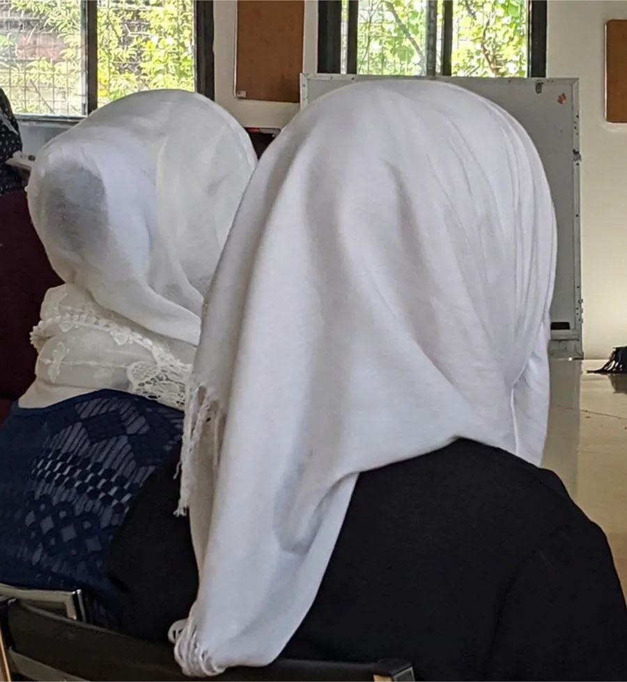 Two women in white head coverings, seen from behind